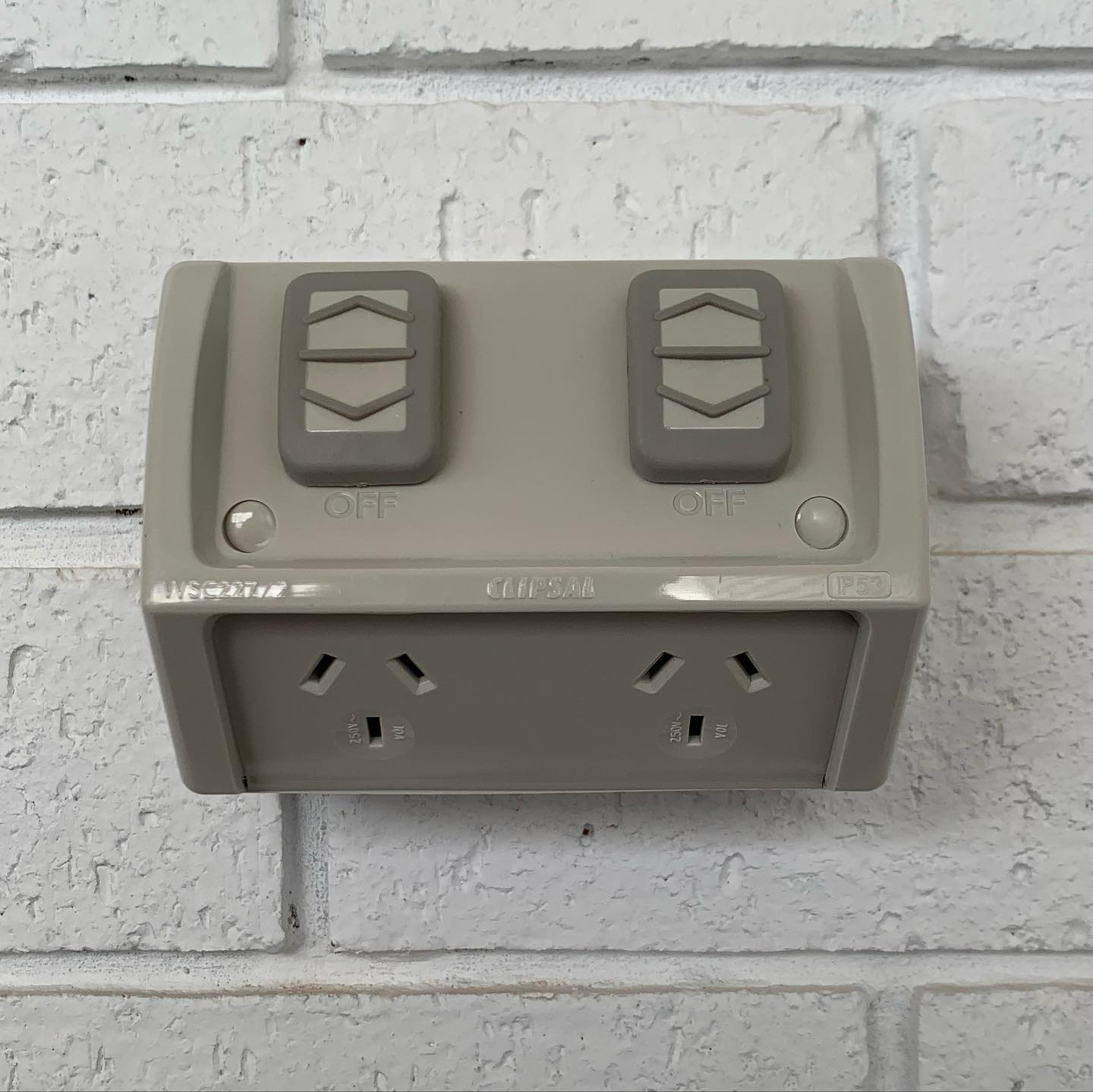 Weatherproof double power point on a painted brick wall